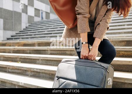 Cropped image of woman pulling big suitcase when walking up the stairs to railway station Stock Photo