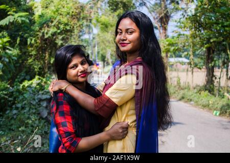 Pretty girls embracing on light background. Excited South Asian sisters expressing love. Stock Photo