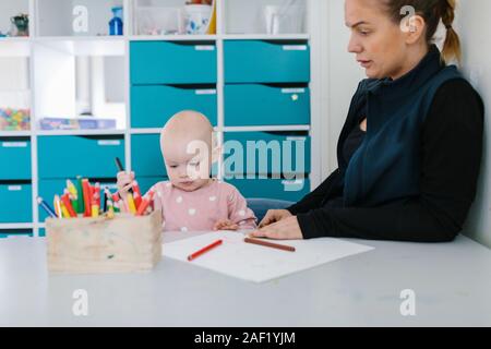 Teacher with toddler in playschool Stock Photo