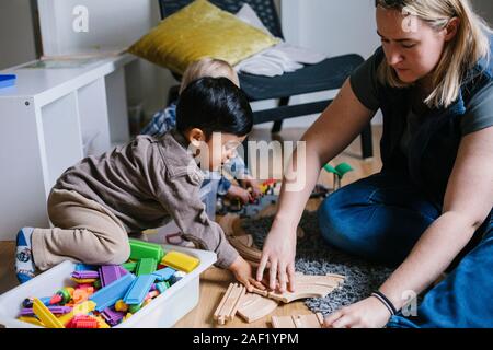 Teacher playing with boy in preschool Stock Photo