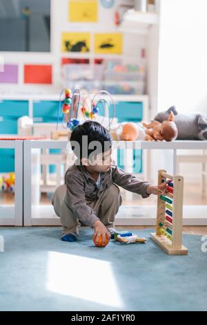Boy in preschool playing with abacus Stock Photo