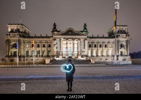 Girl makes heart with light paiting infront of Reichstag building in Berlin, Germany on Christmas. Stock Photo