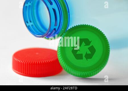 Plastic bottle and caps with recycle symbol on white background - Concept of recyclable items and materials Stock Photo