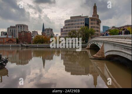 View along the Zhapu Road Bridge to the old quarter, Shanghai, China. Autumn scene with cloudy sky and city buildng reflections in the Suzhou River Stock Photo