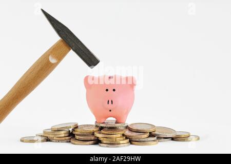 Piggy bank on piles of coins and a hammer Stock Photo