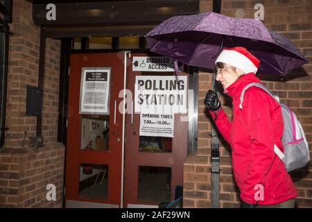 Kidderminster, UK. 12th December, 2019. In spite of freezing temperatures and heavy rain, UK voters seem to be in festive mood as they brave the elements and head to Great Britain's polling stations ensuring their votes are cast in today's General Election. A lady wearing a seasonal Santa hat brings a smile and some much-needed Christmas spirit to voters at this Worcestershire polling station. Credit: Lee Hudson/Alamy Live News Stock Photo