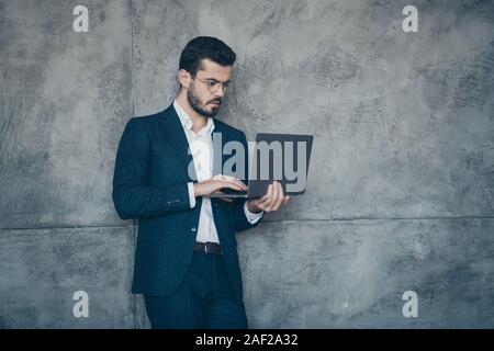 Portrait of his he nice attractive imposing luxurious focused concentrated bearded guy financier wearing jacket using laptop isolated over grey Stock Photo
