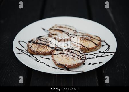 homemade chocolate pancakes served on a white plate over black texture background. Beautiful pancakes. Stock Photo
