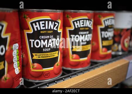 Tins of the Famous Heinz Tomato Soup sauce sat on a supermarket shelf.  H. J. Heinz Company, better known as Heinz, is an American food processing com Stock Photo