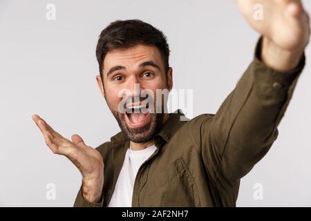 Happy and cheerful, glad young man introduce something as talking on online record video and describe product, hold smartphone extended arm, taking Stock Photo