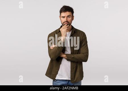 Thoughtful, serious smart bearded man listen friend demand trying solve problem, standing pensive, making difficult choice, touching chin, raise Stock Photo