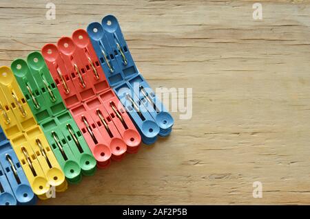 colorful plastic clothes peg clipping hard white paper on wooden board Stock Photo