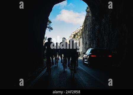 Team of road bikers ride in tunnel while training in mountains