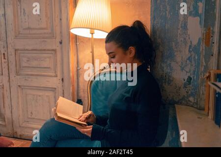 Young Beautiful Woman Reading a Book Be Seated At Table In Cafe With Bohemian Style. Concept of Slow Lifestyle. Attractive Female Student Learning at Stock Photo