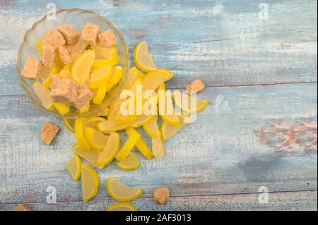 Marmalade lemon slices and pieces of brown sugar on a wooden background. Sweet dessert. Close up Stock Photo