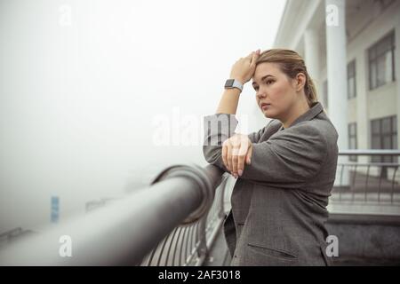 Pensive young woman standing on the balcony Stock Photo