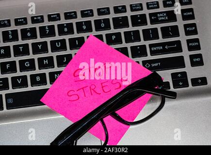 Writing on colorful sticky note Stop stress. Text with Stop stress on paper. Sticky note, post it, glasses on keyboard. Stock Photo