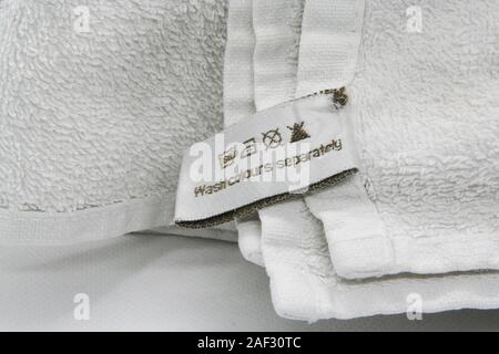 Washing instructions clothes label on white cotton as a background. White bathroom towels. Stock Photo