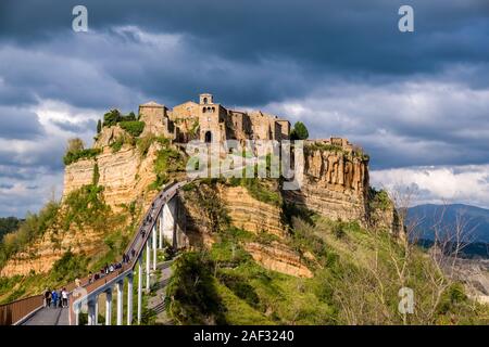 Civita di Bagnoregio, an old etruscan settlement, located on top of a volcanic tuff plateau, illuminated by the setting sun, dark thunderstorm clouds Stock Photo