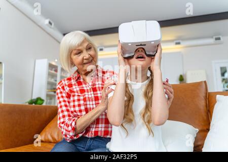 Smiling grandparent embracing her grandchild in VR goggles Stock Photo