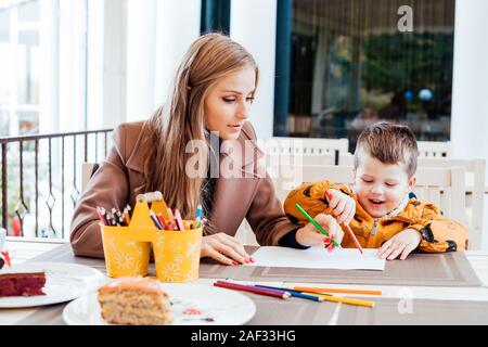 mother and son in the restaurant painted pencils before eating Stock Photo