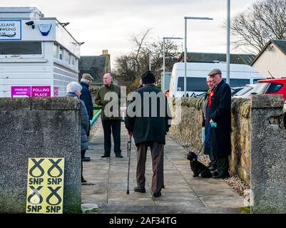 Gullane Bowling Club, East Lothian, Scotland, United Kingdom, 12th December 2019. UK election: voters going into the local polling place with local activists and a man holding a dog on a lead Stock Photo