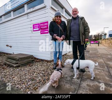 Gullane Bowling Club, East Lothian, Scotland, United Kingdom, 12th December 2019. UK election: a couple with dogs voting at the local polling place Stock Photo