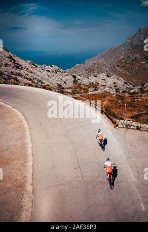 Couple ride together on road bicycle in mountains. Sea in background. Mallorca, Spain Stock Photo