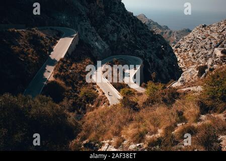 Silhouette of cyclist on road bicycle, ride down hill in mountains. Beautiful scenery, Aerial view Stock Photo