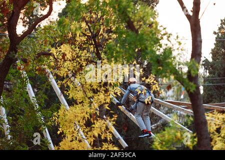 Climber in equipment trains to walk on sheer wooden bars. Stock Photo