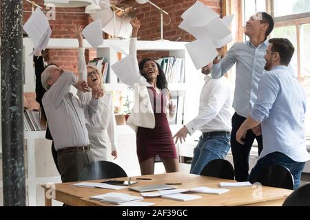 Happy colleagues celebrating successful project accomplishment throwing papers up Stock Photo