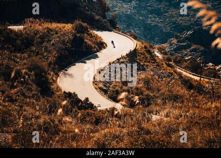 Silhouette of biker who ride on road bicycle in mountains Stock Photo