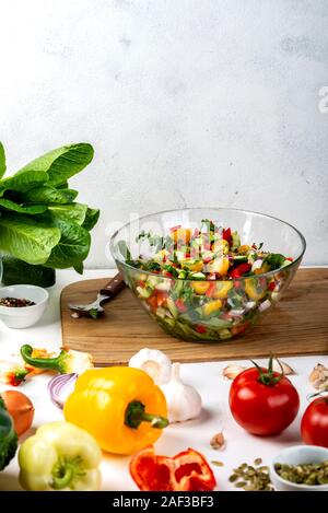 Bowl full of salad from different eco vegetables with ingredients and spices on the table. Healthy diet food concept. Stock Photo