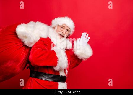 Santa claus waving and carrying a sack of presents isolated on white ...