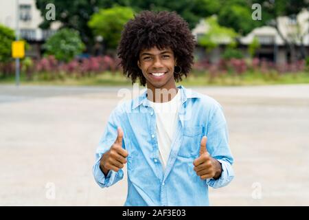 Happy african american hipster young adult showing thumbs up outdoor in summer in city Stock Photo