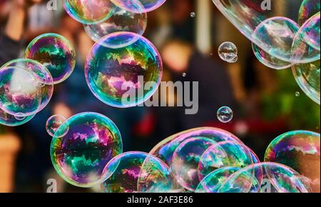 Metallic glowing colorful soap bubbles in the air in front of a blurry abstract background Stock Photo