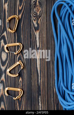 Tools on the left and cable on the right side. Isolated photo of climbing equipment. Part of carabiner lying on the wooden table Stock Photo