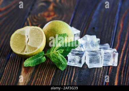 Ingredients for cocktail on the wooden floor. Lime, leaf of mint and ice cubes Stock Photo