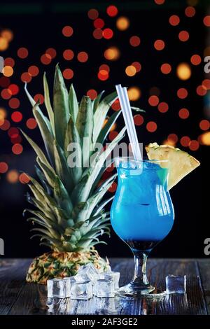 Top of pinaple lying near drink. Cocktail is ready. On the wooden table in the night club. Nice lighting Stock Photo