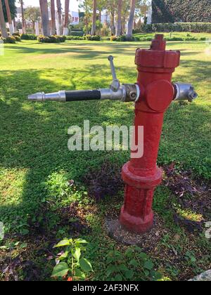 Vintage Red Fire Hydrant in the hotel garden, for safety and water in case of fire. Red on green. Stock Photo