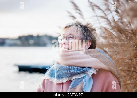 Portrait of woman in her 60's looking happy sitting outside in fall. Stock Photo