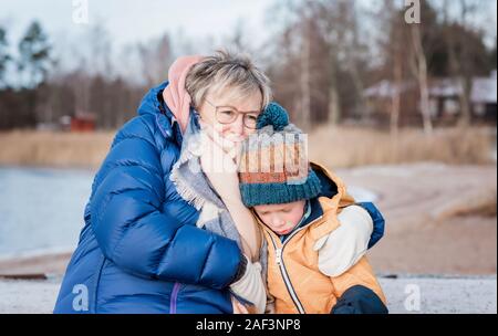 grandmother comforting her grandson whilst playing outside in winter Stock Photo