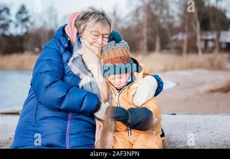 grandmother hugging her grandson to comfort him whilst outside Stock Photo