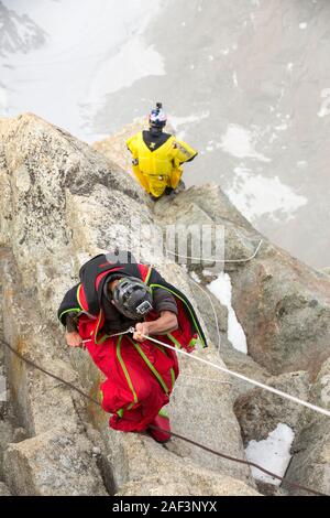 Base jumpers wearing wing suites prepare to jump from the Aiguille Du midi above Chamonix, France. Stock Photo