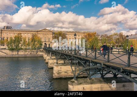 Paris, France - November 7, 2019: Wooden pedestrian bridge of the Arts and the Louvre museum, with the Square Courtyard (Cour Carrée) entrance Stock Photo