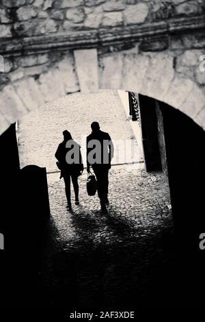 Silhouette of a man and woman walking through an tunnel like passage Stock Photo