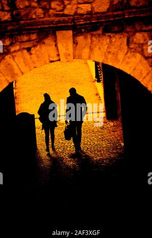 Silhouette of a man and woman walking through an tunnel like passage Stock Photo