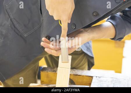 Hands of carpenter with chisel in the hands on the workbench in carpentry Stock Photo