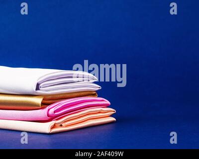 rolls of silk of different colors folded stack. colorful fabric silk stack background Stock Photo