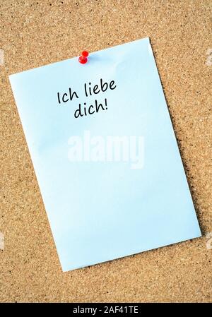 Large white note on a pin board with the German words "I love you" as a message from the partner Stock Photo